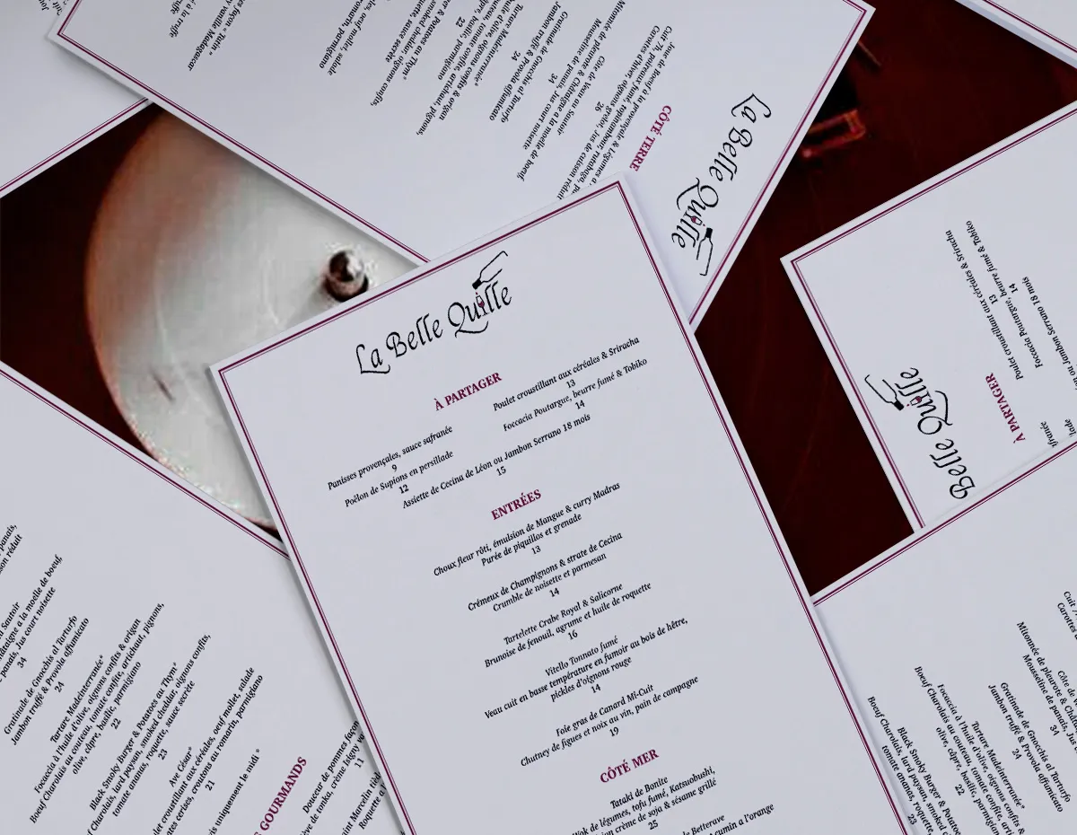 Plusieurs exemplaires du menu du restaurant La Belle Quille disposés en éventail, montrant la carte des entrées et des plats.
