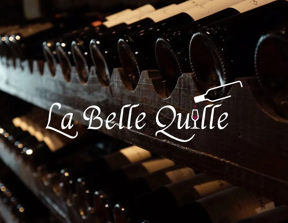 Logo blanc du restaurant La Belle Quille superposé sur une cave à vin en bois avec des bouteilles de vin.