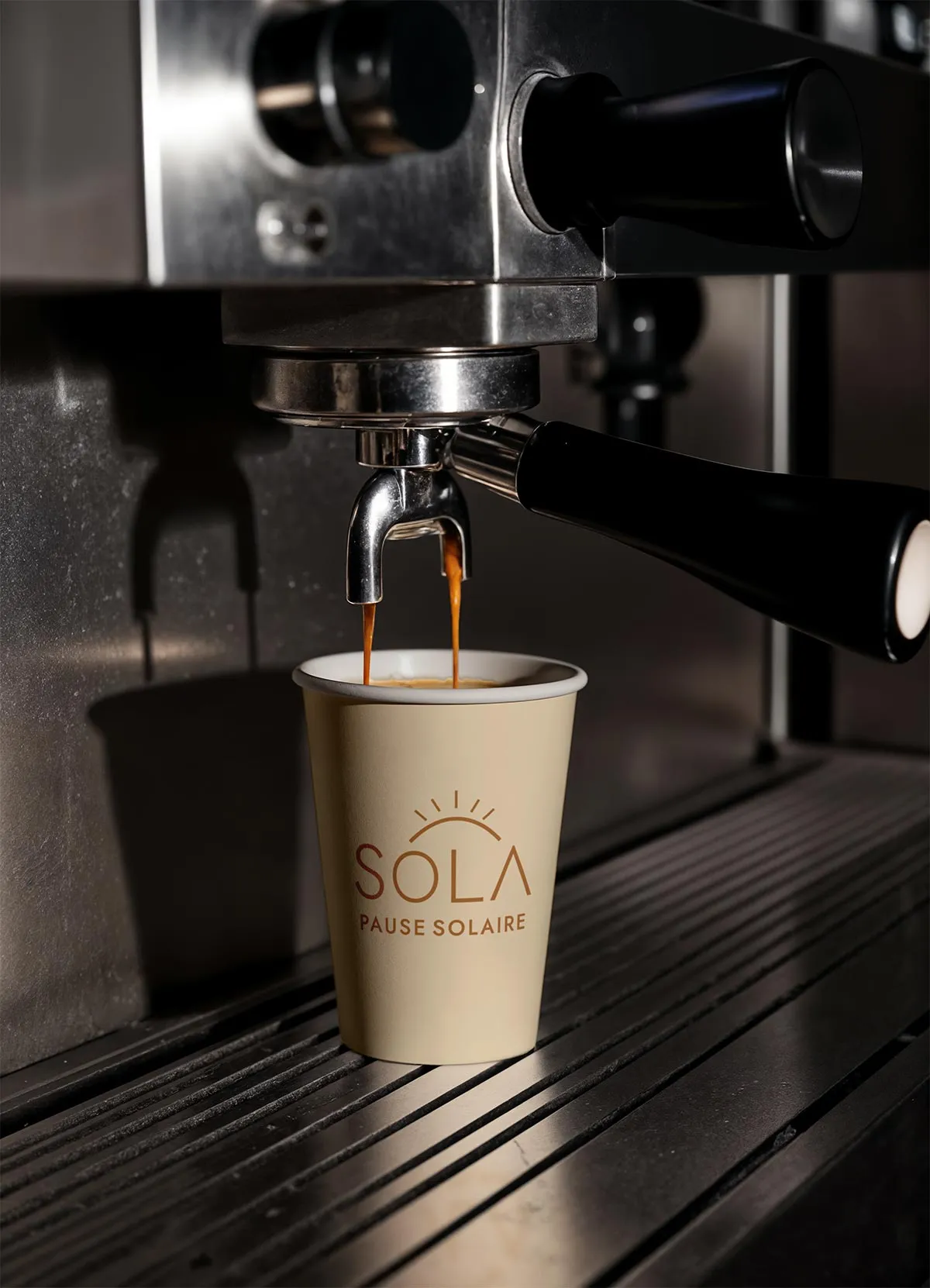 Gobelet en carton avec le logo SOLA sous une machine à café expresso professionnelle.